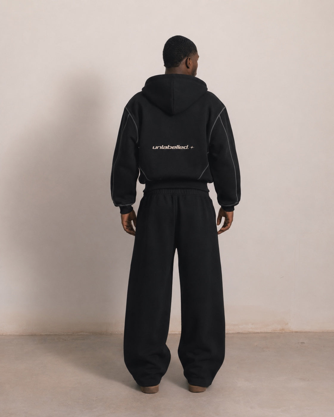 Black outer-stitched hoodie and sweatpants, back view